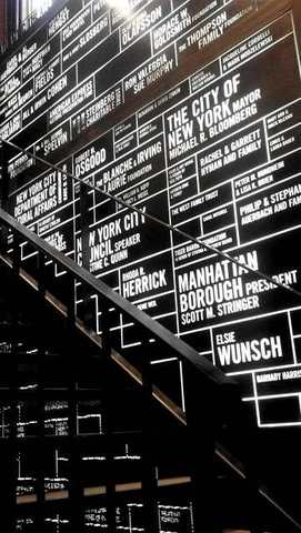 Lit donor wall over a lobby stair