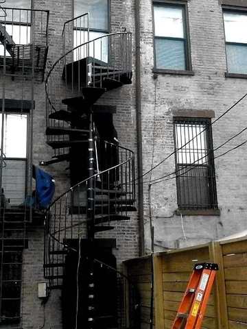Exterior steel spiral stair against a brick building